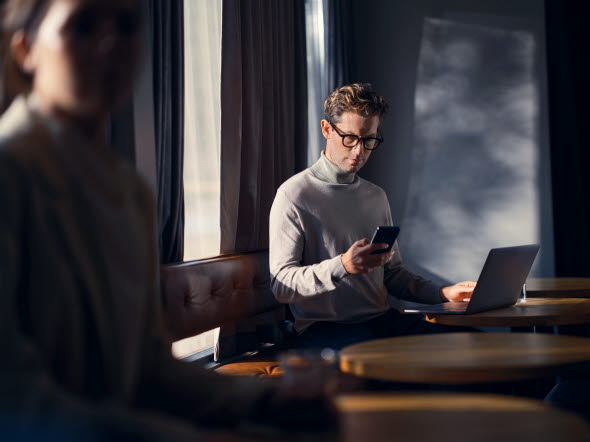 Bild på en man som står i ett mötesrum med en laptop.