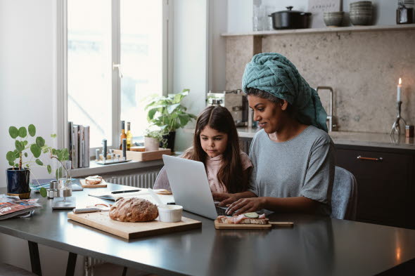 Mor och dotter som sitter och tittar på en laptop tillsammans