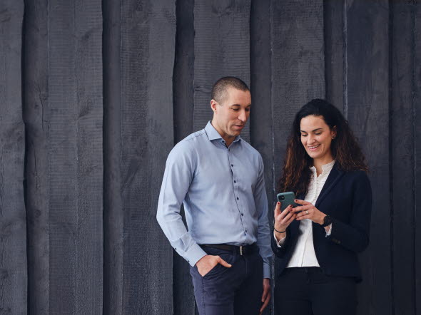 Två personer som tittar i en telefon.
