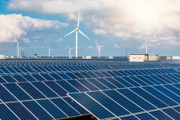 Tak med solceller i förgrunden och vindkraftsverk i bakgrunden