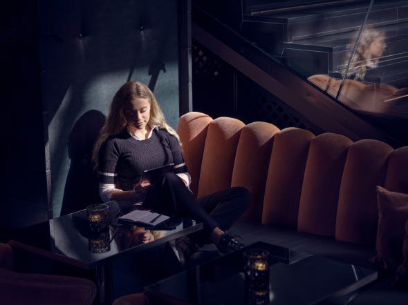 Bild på en kvinna som sitter på et café med en läsplatta.
