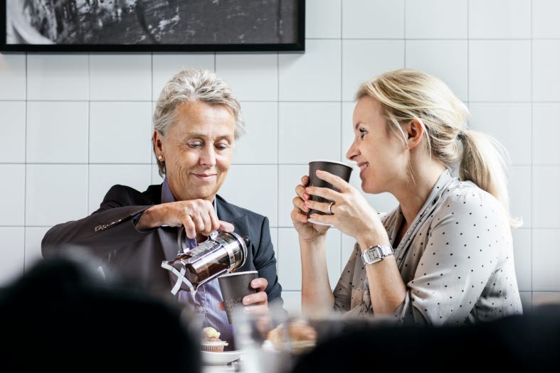 Bild på en äldre kvinna som dricker kaffe med en yngre kvinna.