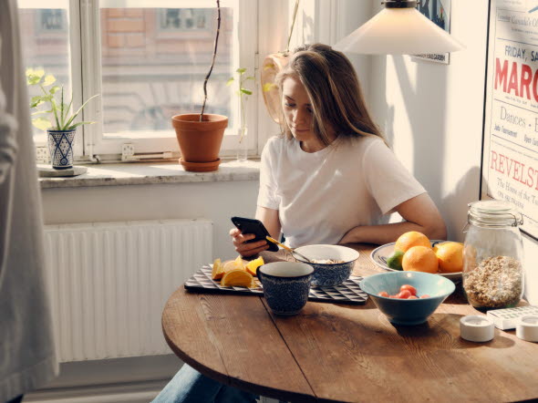 Kvinna på café tittar i mobilen