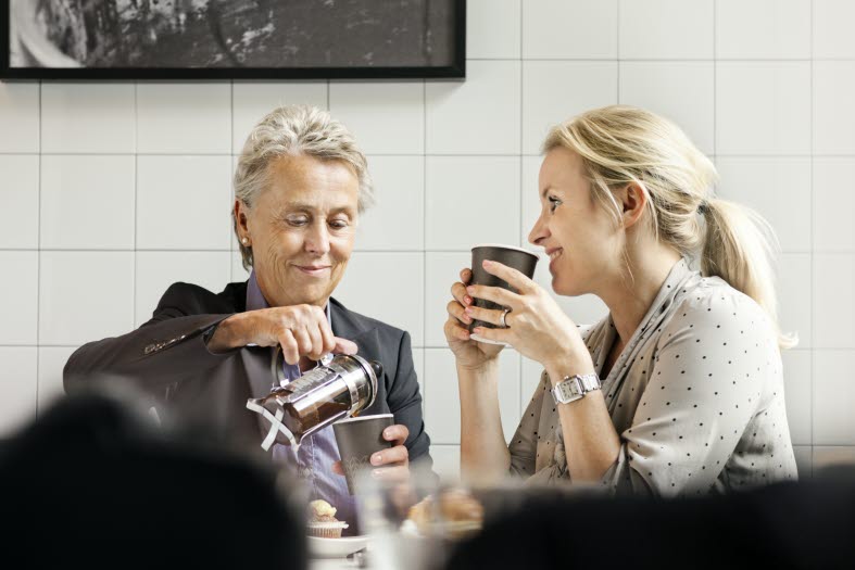 Bild på en äldre och en yngre kvinna som dricker kaffe tillsammans.