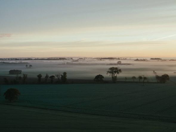 Solen går upp över dimmigt landskap