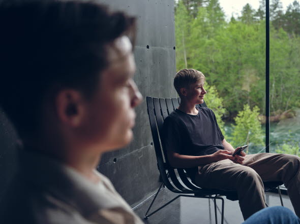 Bild på en man som sitter på en altan framför en skog.