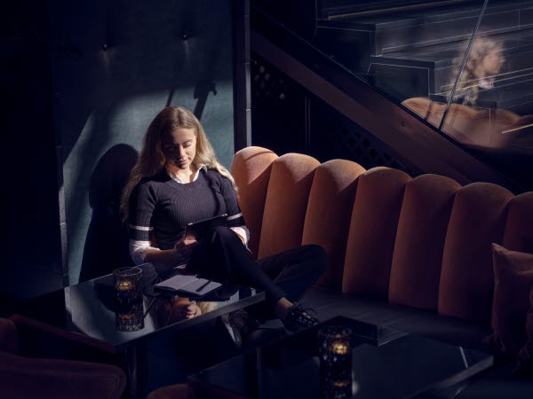 Bild på en kvinna som sitter på ett café och tittar på en läsplatta.