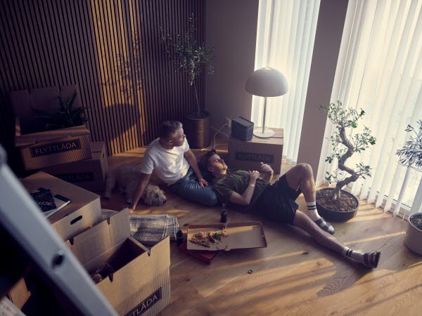 Två män tar en paus med pizza i ett flyttkaos.