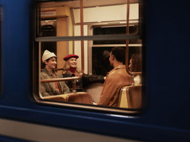 Fyra unga personer sitter i tunnelbannan tillsammans och skrattar och pratar.