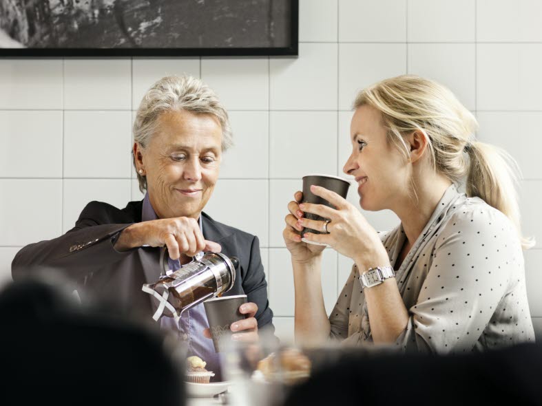 Bild på en äldre och en yngre kvinna som dricker kaffe tillsammans.