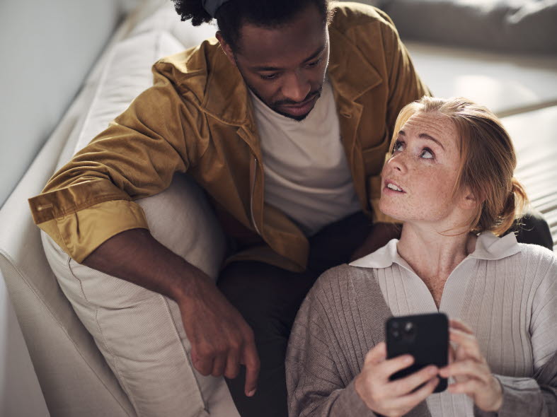 Kvinna och man i en soffa tittandes på varann