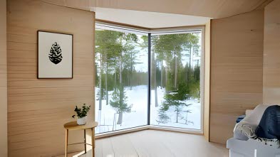 Utsikt över vinterlandskap innifrån ett ombonat rum. 