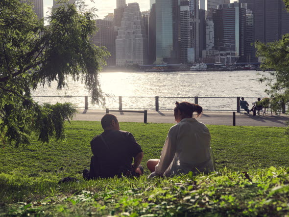 En man och en kvinna som sitter i gräset i en park och pratar med varann.